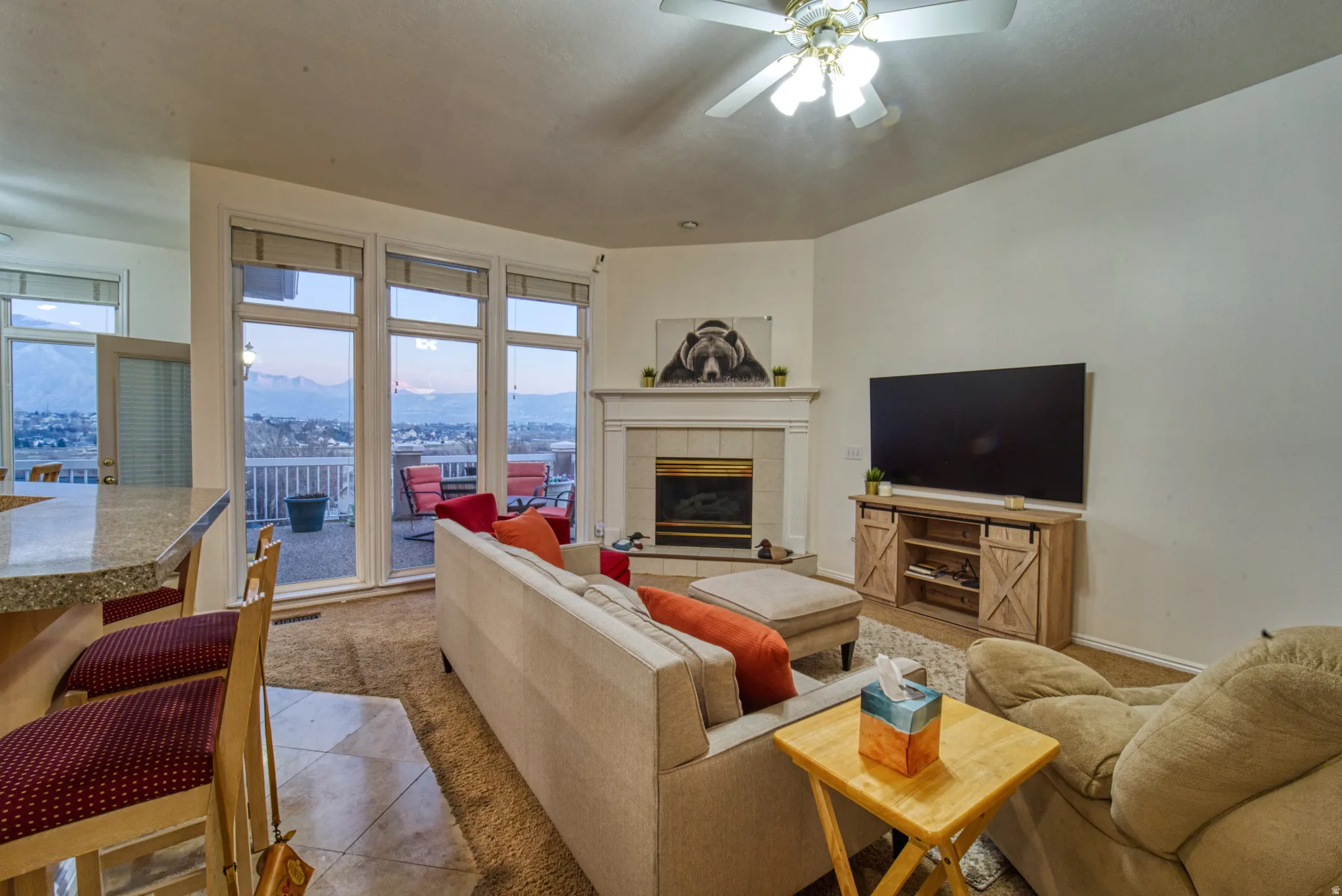 Living area with a built-in fireplace, ceiling fan, and large windows