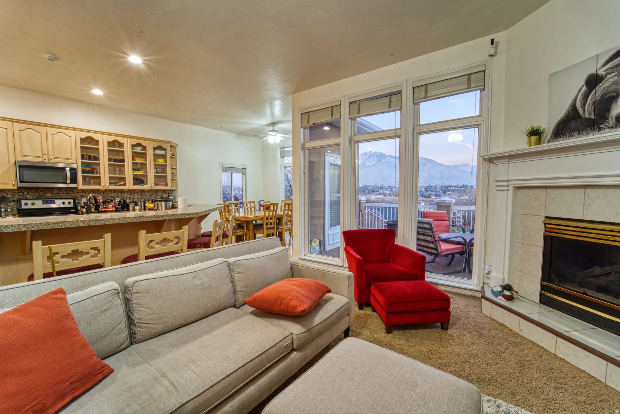 Living area featuring a floor-to-ceiling fireplace with tile surround, a built-in mantel, and large windows offering a mountain backdrop