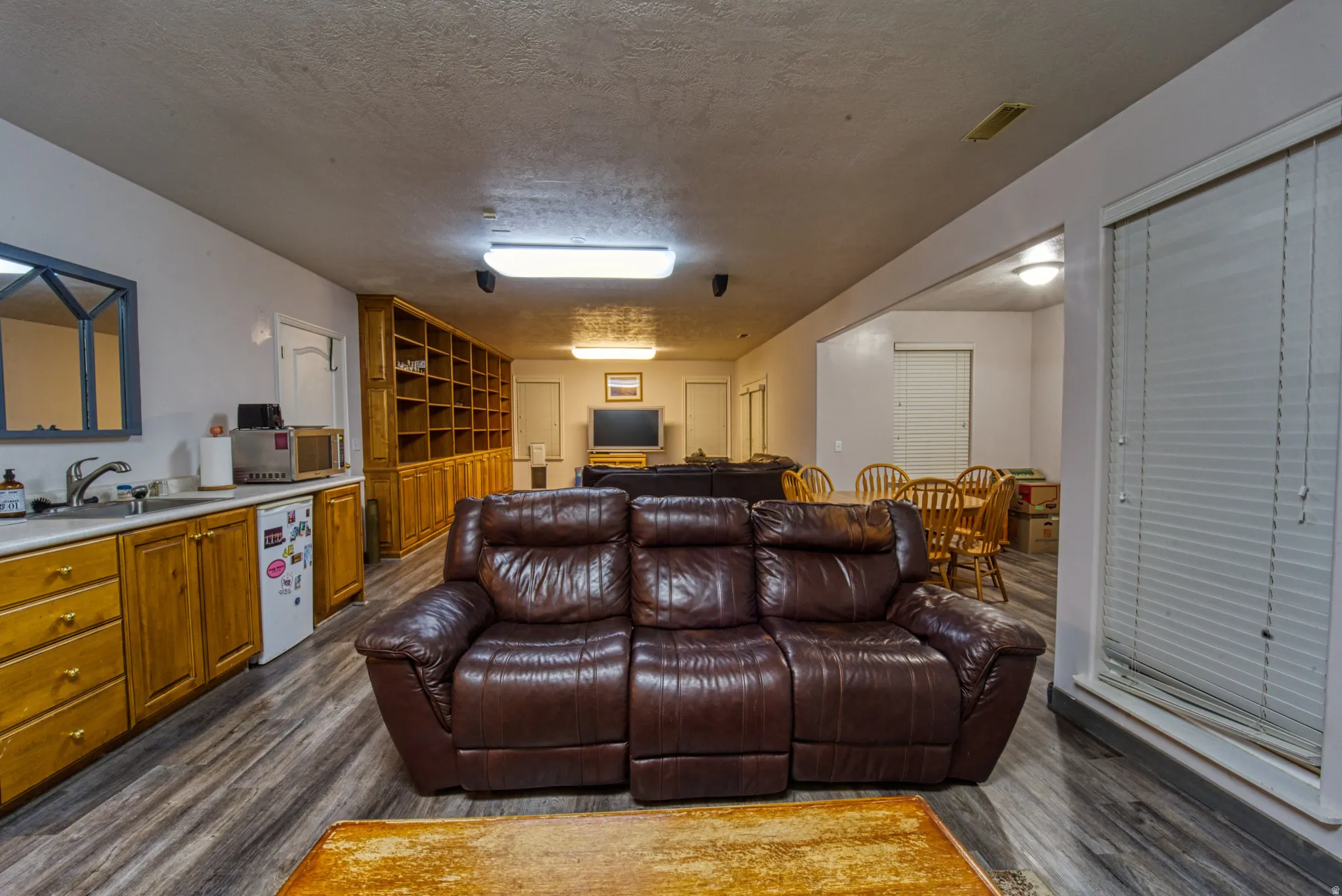 Open-concept living space featuring wood-finish flooring and a built-in wet bar with a stainless steel sink