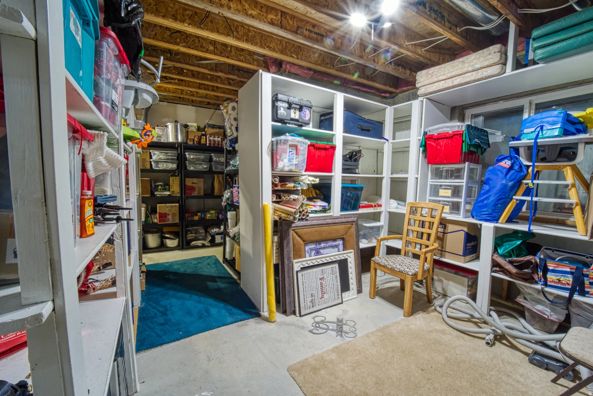 Basement storage area featuring exposed wood joists and concrete flooring