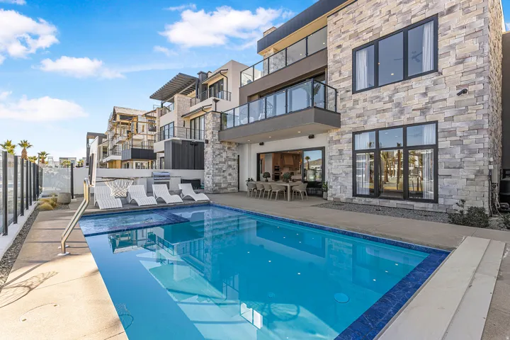 Multi-story residence featuring a stone-clad exterior and multiple balconies with glass railings