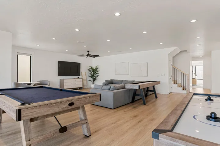Spacious recreational area featuring wood-finish flooring, recessed lighting, and a modern ceiling fan
