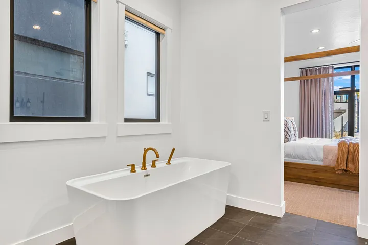 Freestanding bathtub featuring brass fixtures and dual windows