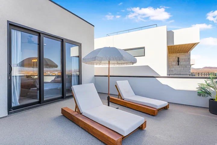 Rooftop deck featuring a light grey textured surface, black-framed sliding glass doors, and a partial privacy wall