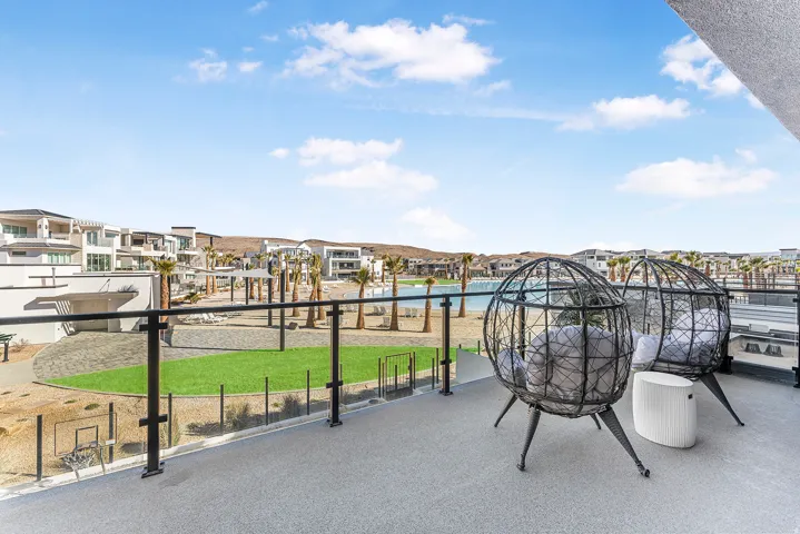 Private balcony with glass railing system overlooking a landscaped common area, water feature, and contemporary architecture