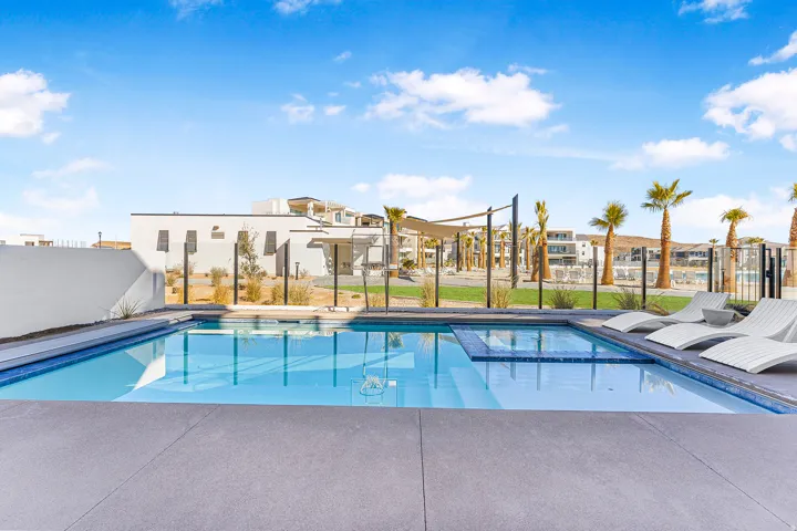Outdoor swimming pool with integrated spa and surrounding concrete decking
