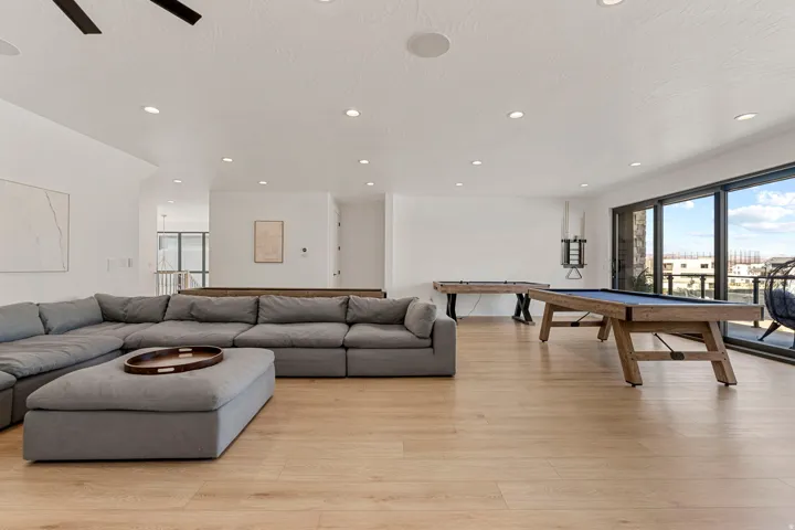 Spacious open-concept room featuring light wood-finish flooring, recessed lighting, and a full wall of sliding glass doors