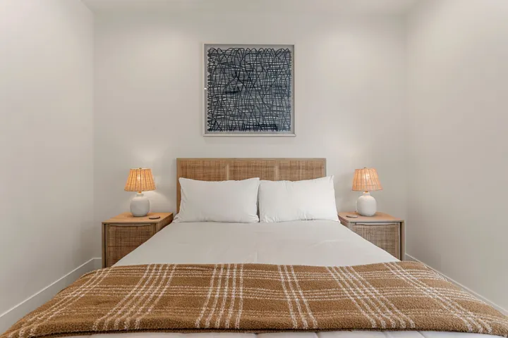 Bedroom featuring a woven headboard, dual integrated nightstands with single drawers, and recessed ceiling lighting