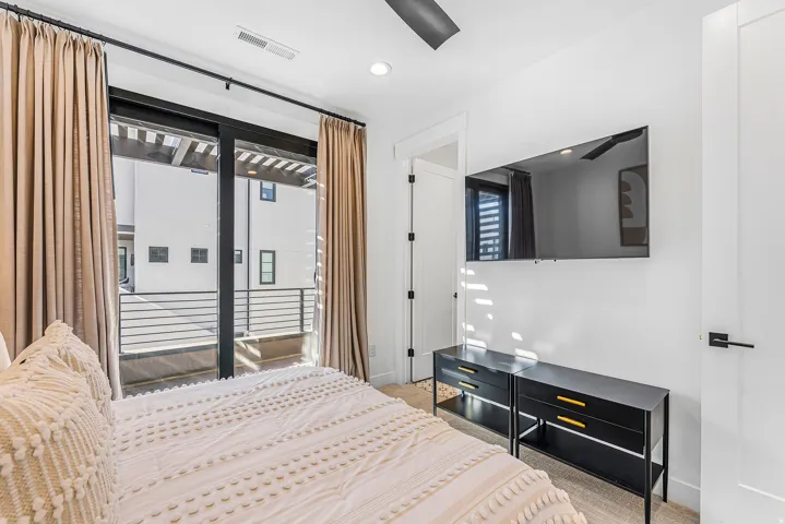 Room featuring a full-light glass sliding door with black framing, leading to an exterior balcony with black metal railings