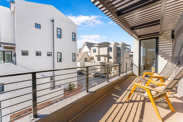 Private balcony featuring a slat-covered pergola, concrete flooring, and metal railings