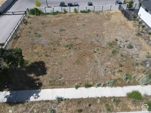 Expansive vacant lot featuring perimeter fencing, an established sidewalk, and street access
