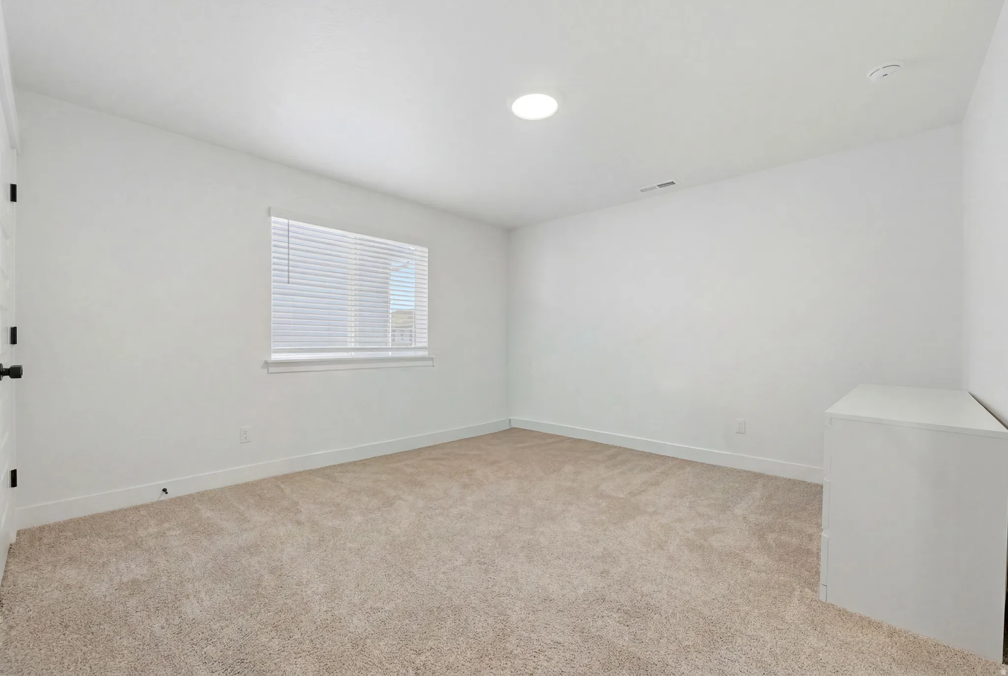 White interior featuring a single window with blinds, recessed lighting, and neutral carpet flooring