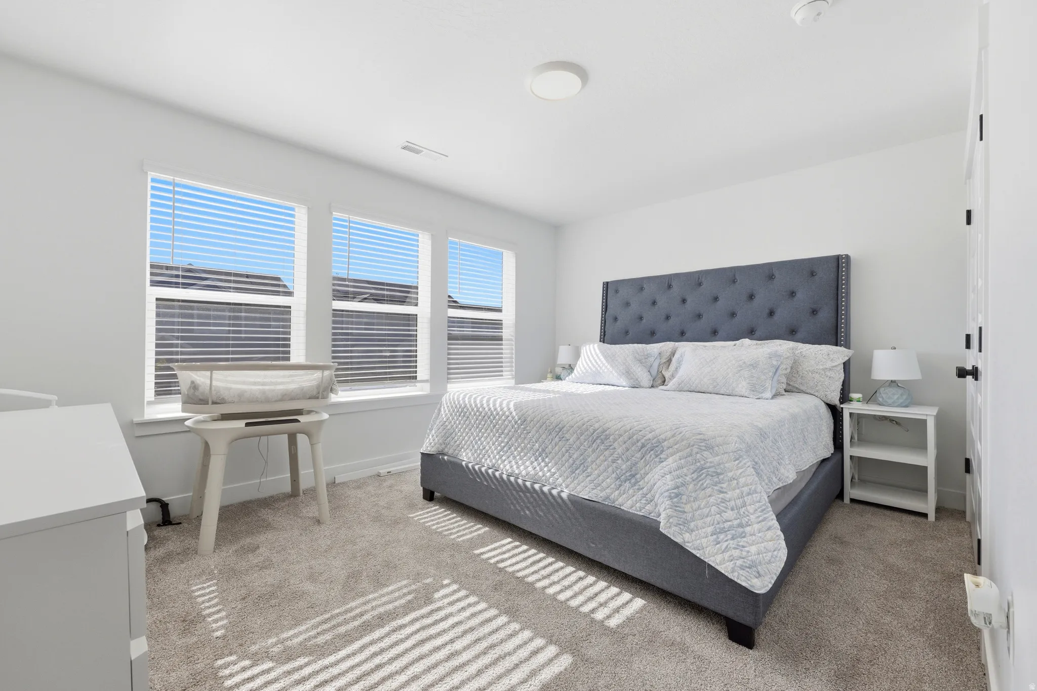 Bright bedroom featuring plush carpeting and a neutral color palette