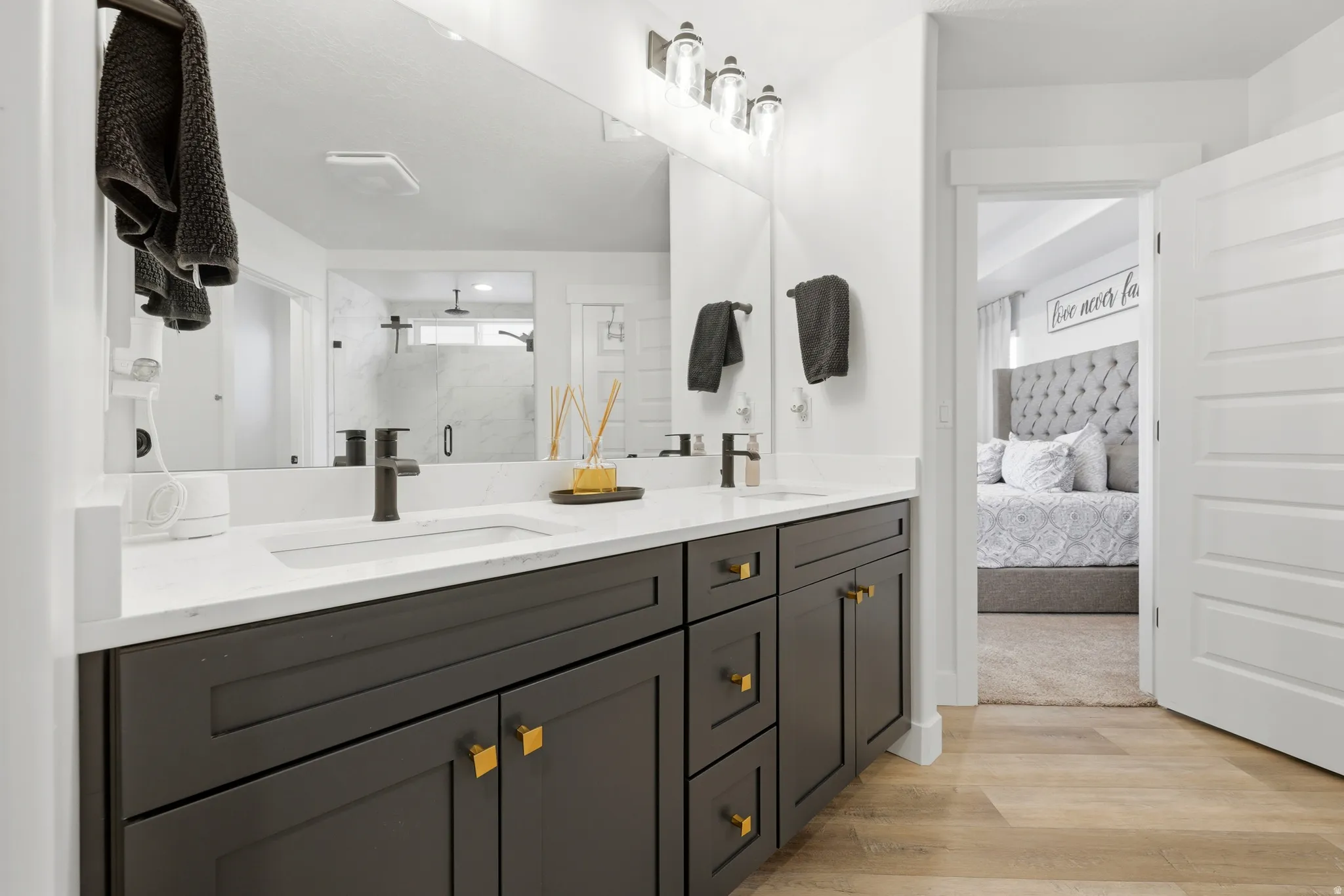 Double vanity with dark wood-finish cabinetry, white countertops, and matte black fixtures