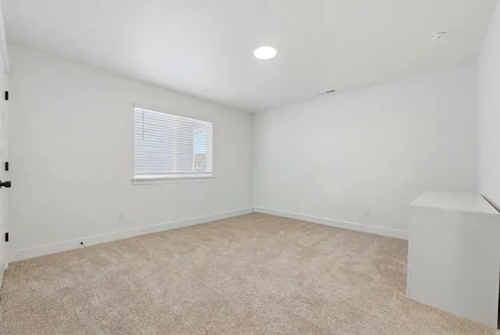 White interior featuring a single window with blinds, recessed lighting, and neutral carpet flooring