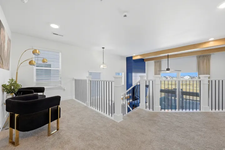 Carpeted upper-level landing featuring white railings with black vertical balusters