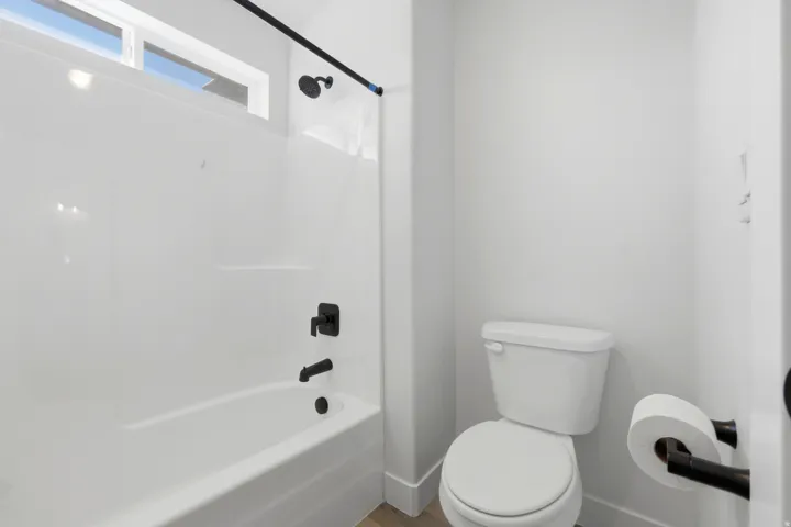Bathroom featuring a white bathtub and shower combination with matte black fixtures