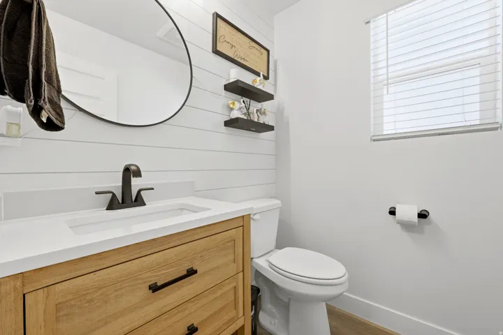 Bathroom featuring a wood-finish vanity with drawer storage, integrated white sink, and dark bronze-tone faucet