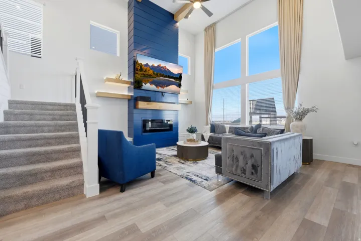 Open-concept living space featuring a two-story ceiling, tall windows with horizontal blinds, and wood-finish flooring