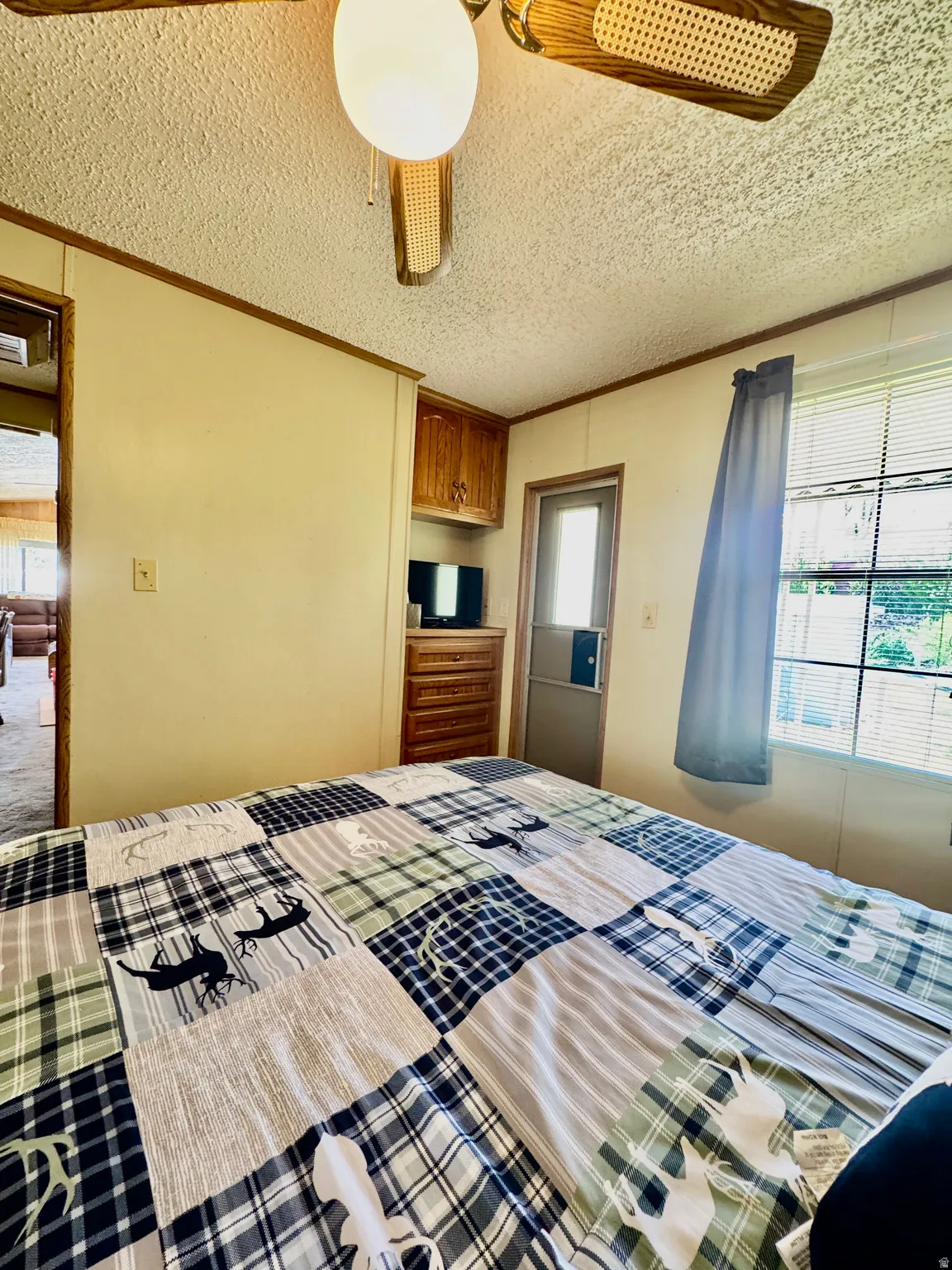 Interior space featuring a ceiling fan with wood-finish blades, a built-in wood-finish cabinet, and a window with blinds