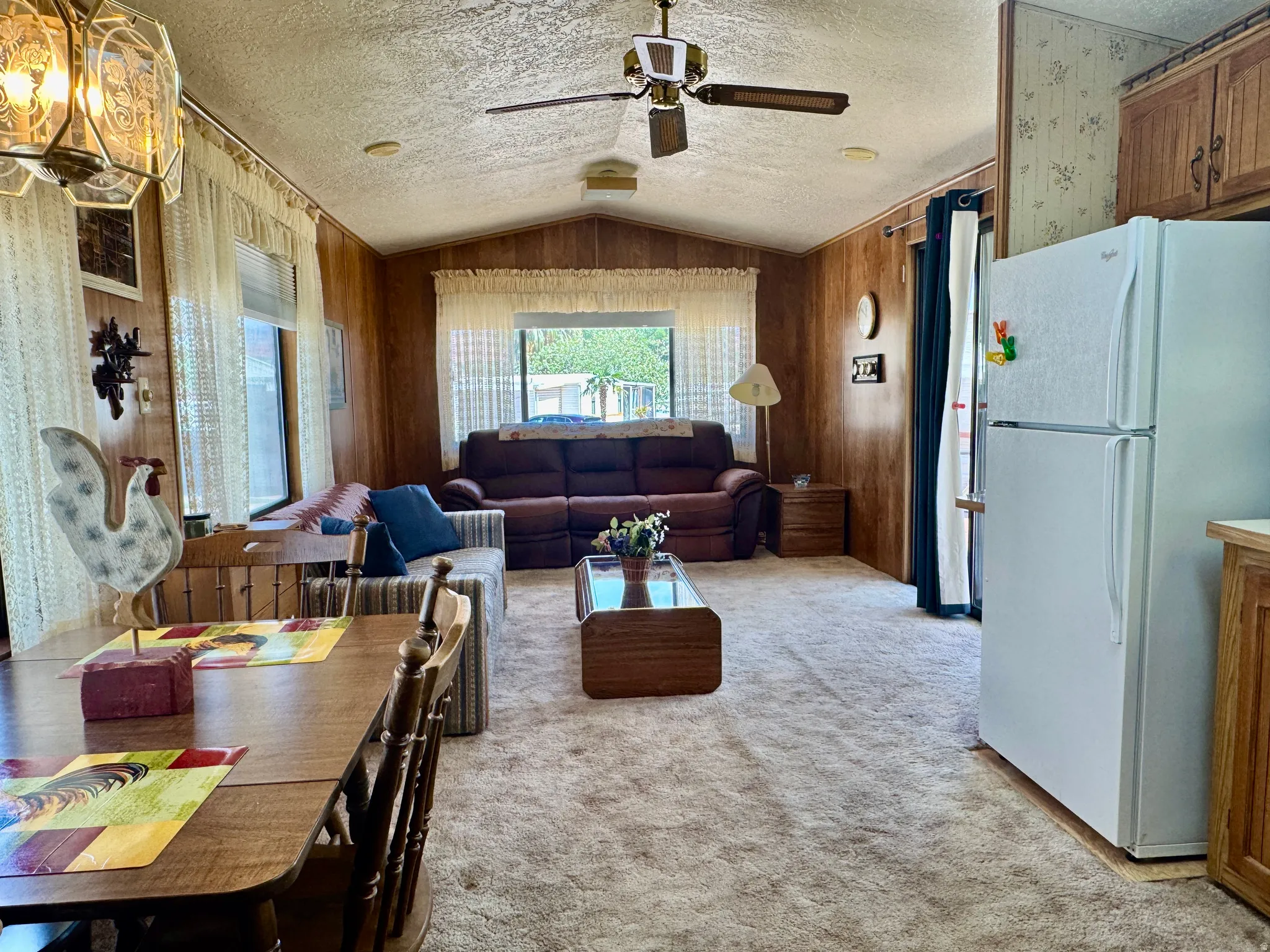 Open-concept living space featuring wood paneling, vaulted ceilings, and a ceiling fan