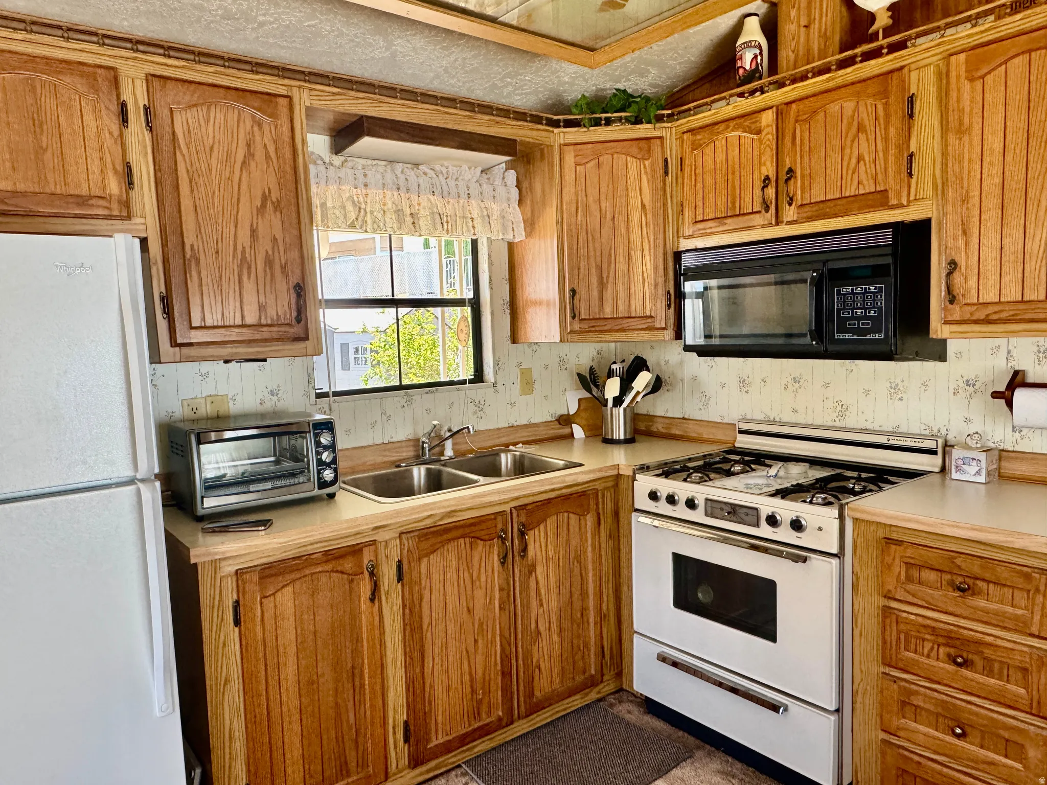 Kitchen featuring wood cabinetry, laminate countertops, double basin sink, and a built-in microwave