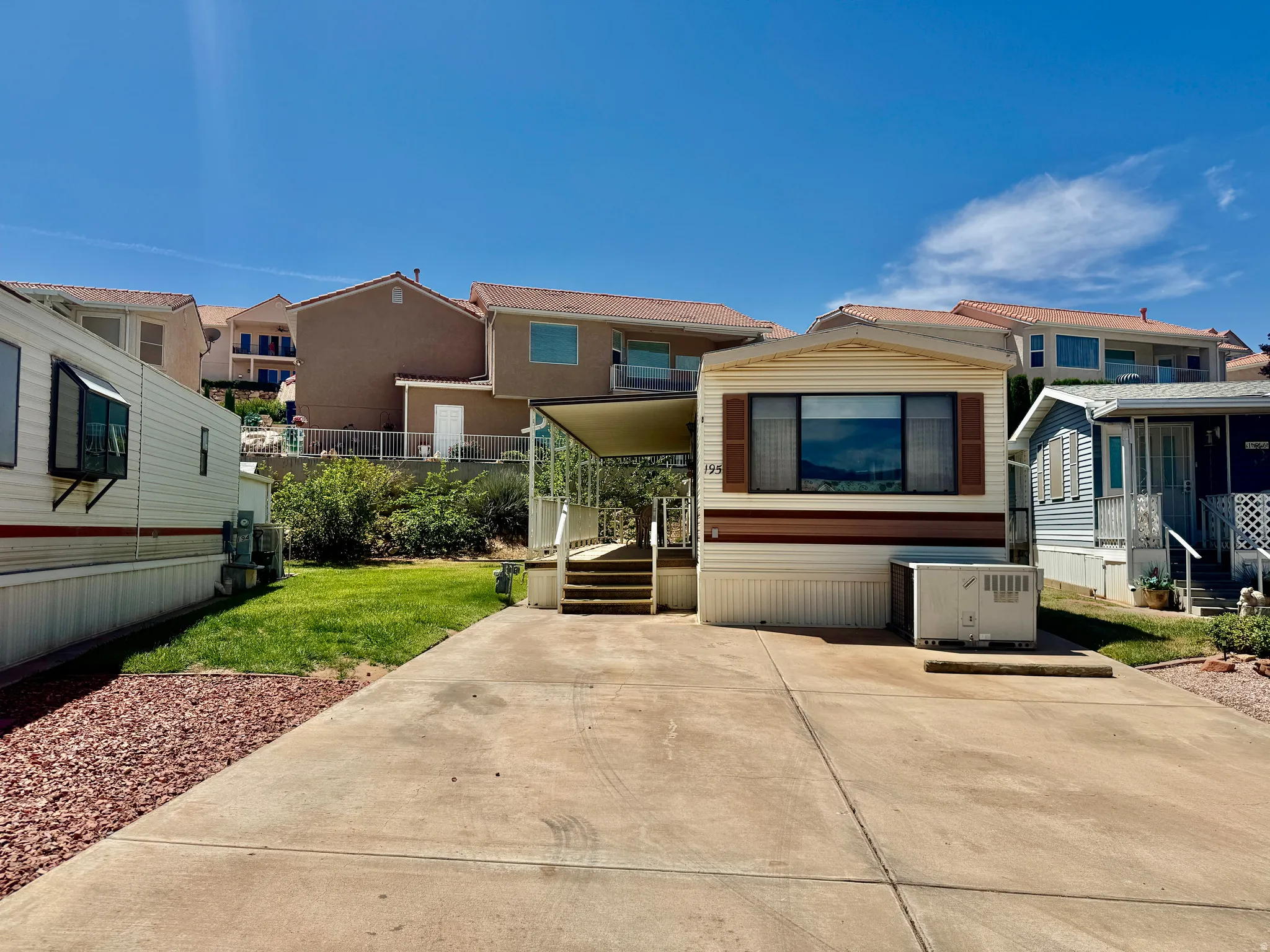 Exterior showcasing a multi-pane window with brown shutters, a covered entry with steps, and a concrete driveway