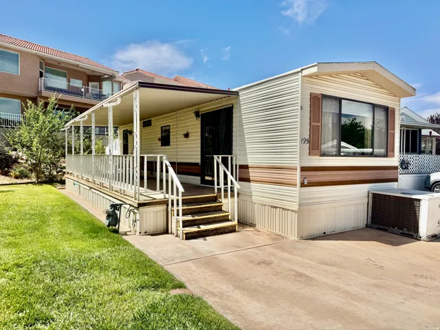 Exterior featuring horizontal siding, an extended covered porch, a concrete driveway, a manicured lawn, and a window with louvered shutters