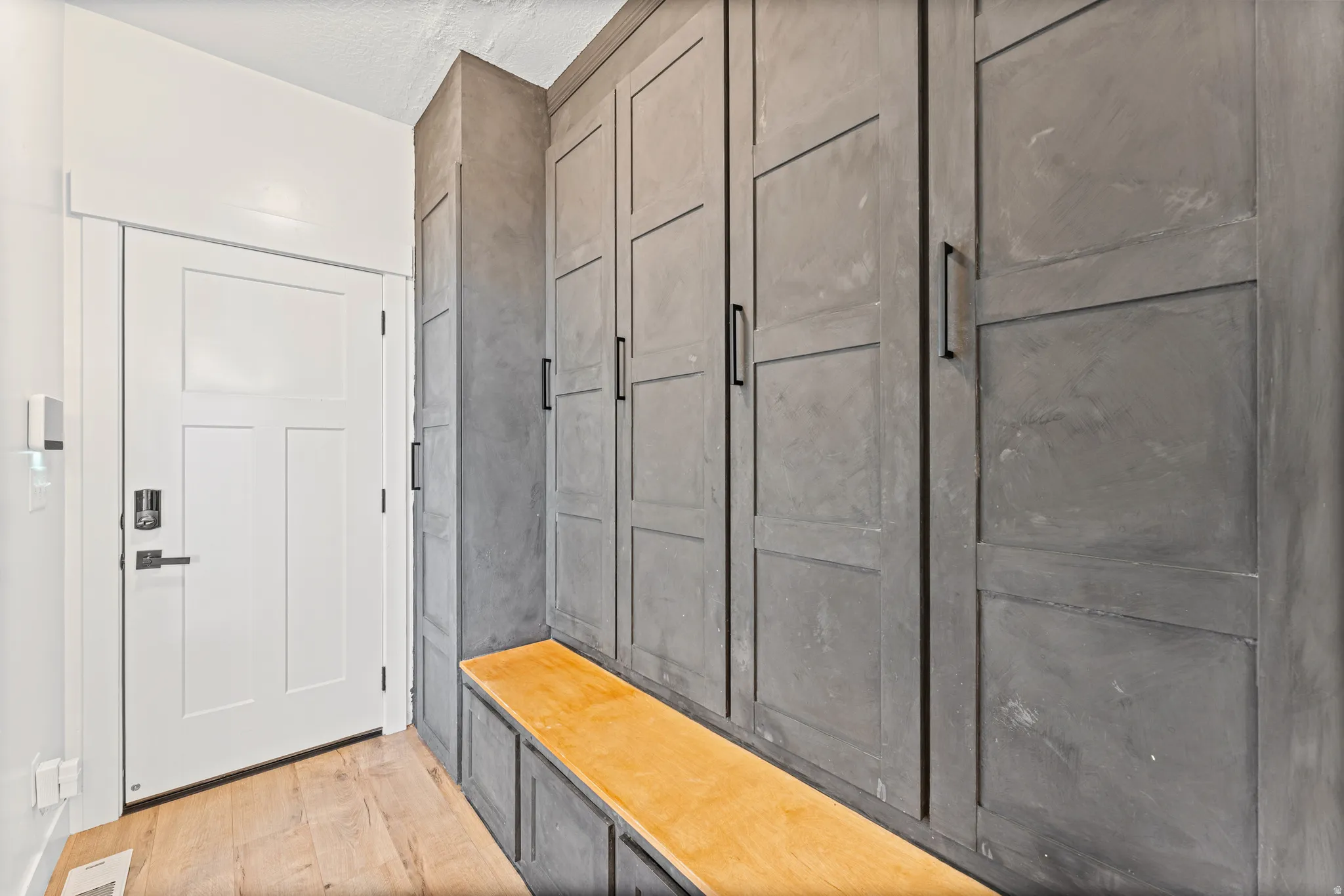 Built-in mudroom cabinetry featuring a solid wood bench, extensive storage, and modern black hardware