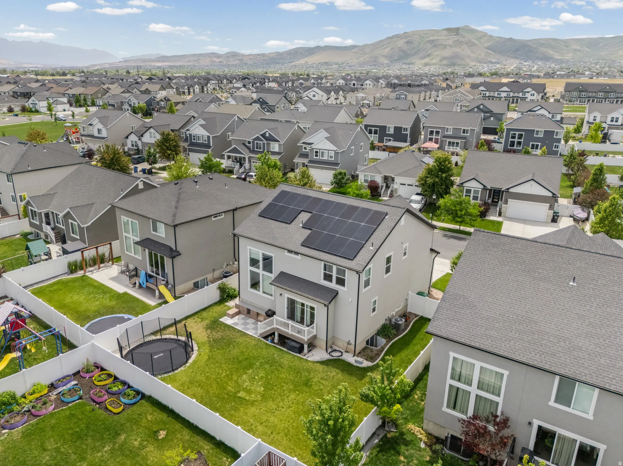 Residential property featuring a light-colored stucco exterior, black roof, and integrated solar panels