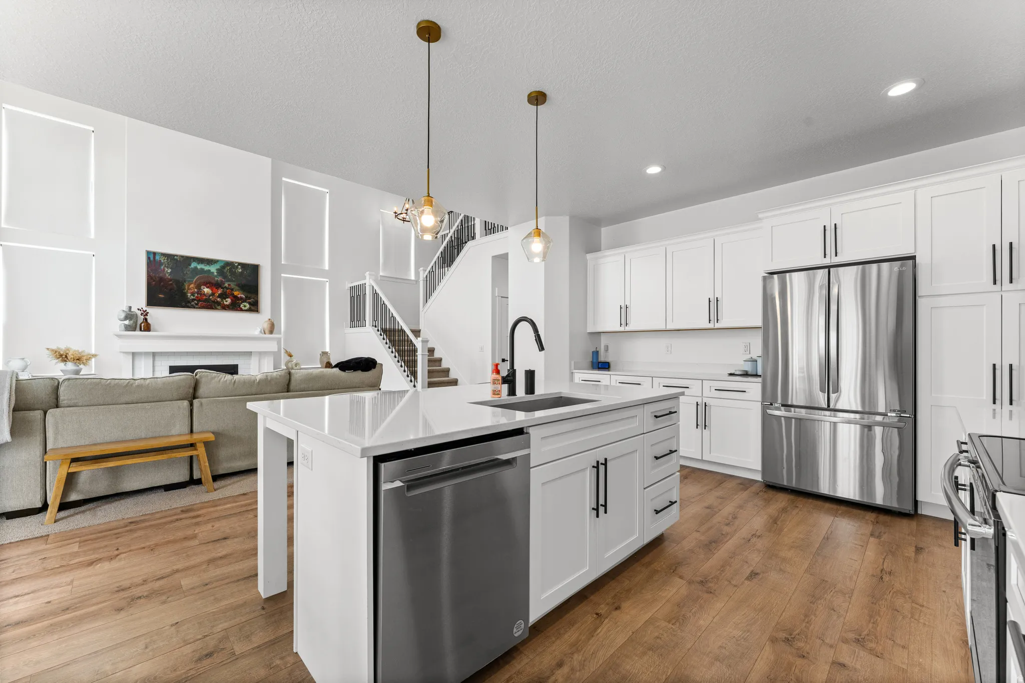 Open concept kitchen featuring white cabinetry, stainless steel appliances, and a central island with a sink
