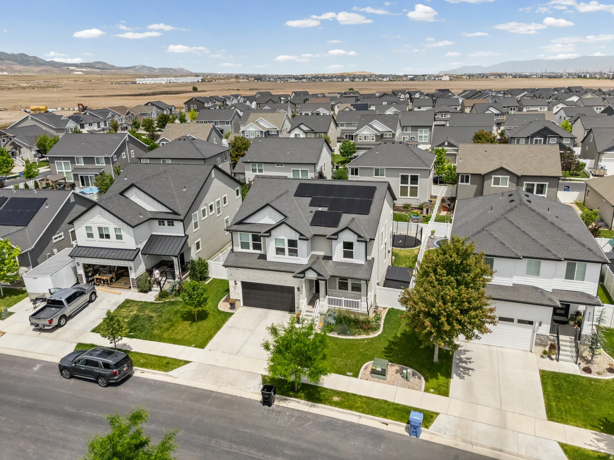Contemporary two-story home featuring a dark gray asphalt shingle roof, solar panels, and a two-car garage
