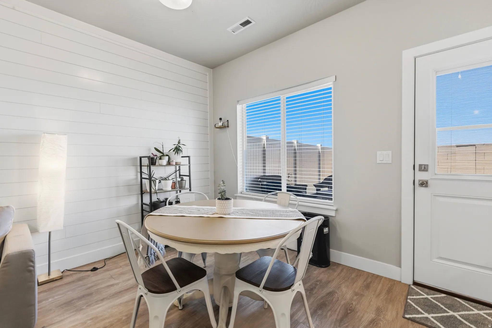 Dining area featuring a shiplap accent wall, wood-finish flooring, and a window with blinds
