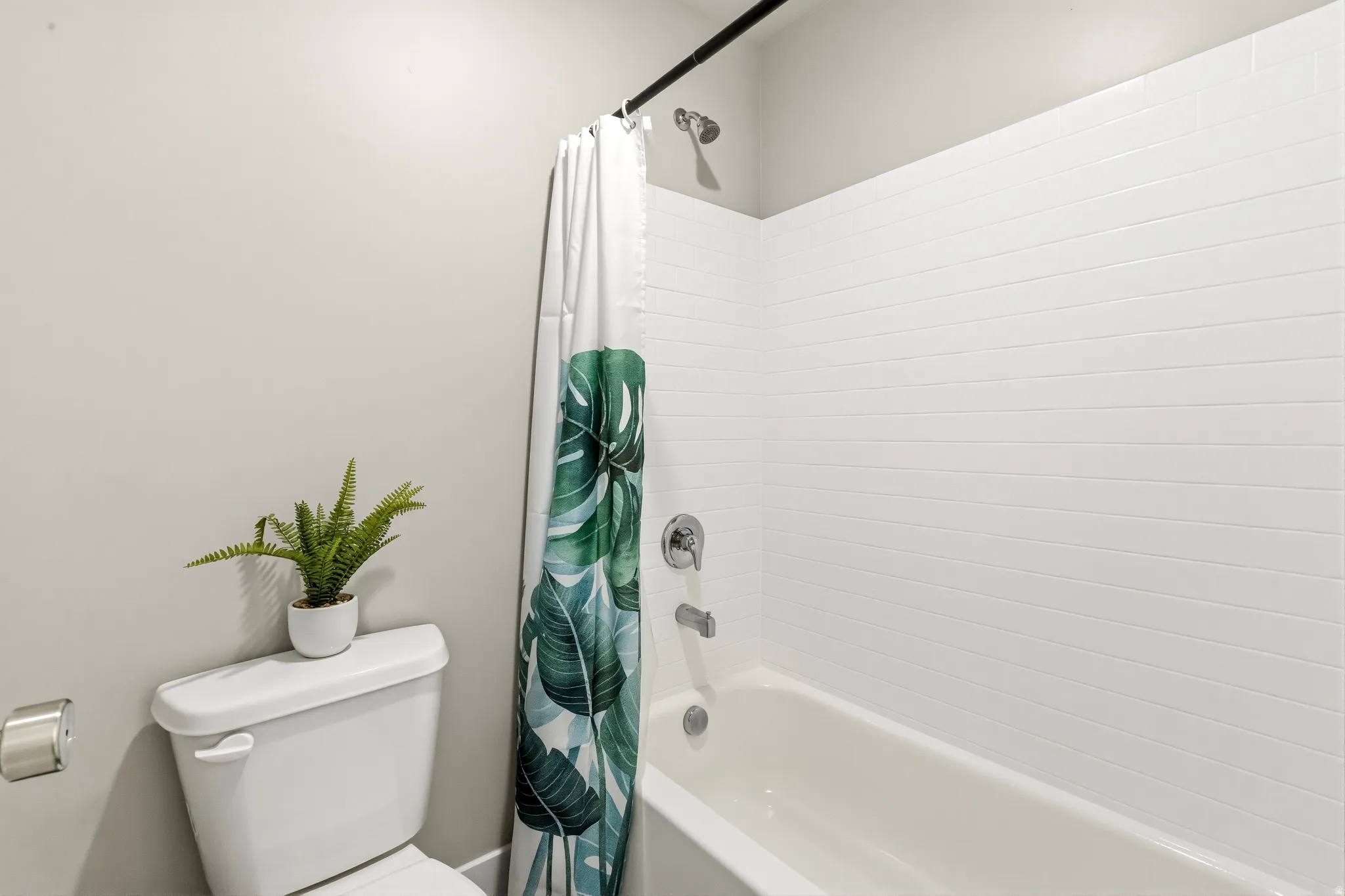 White subway tile shower surround with a built-in tub and chrome fixtures