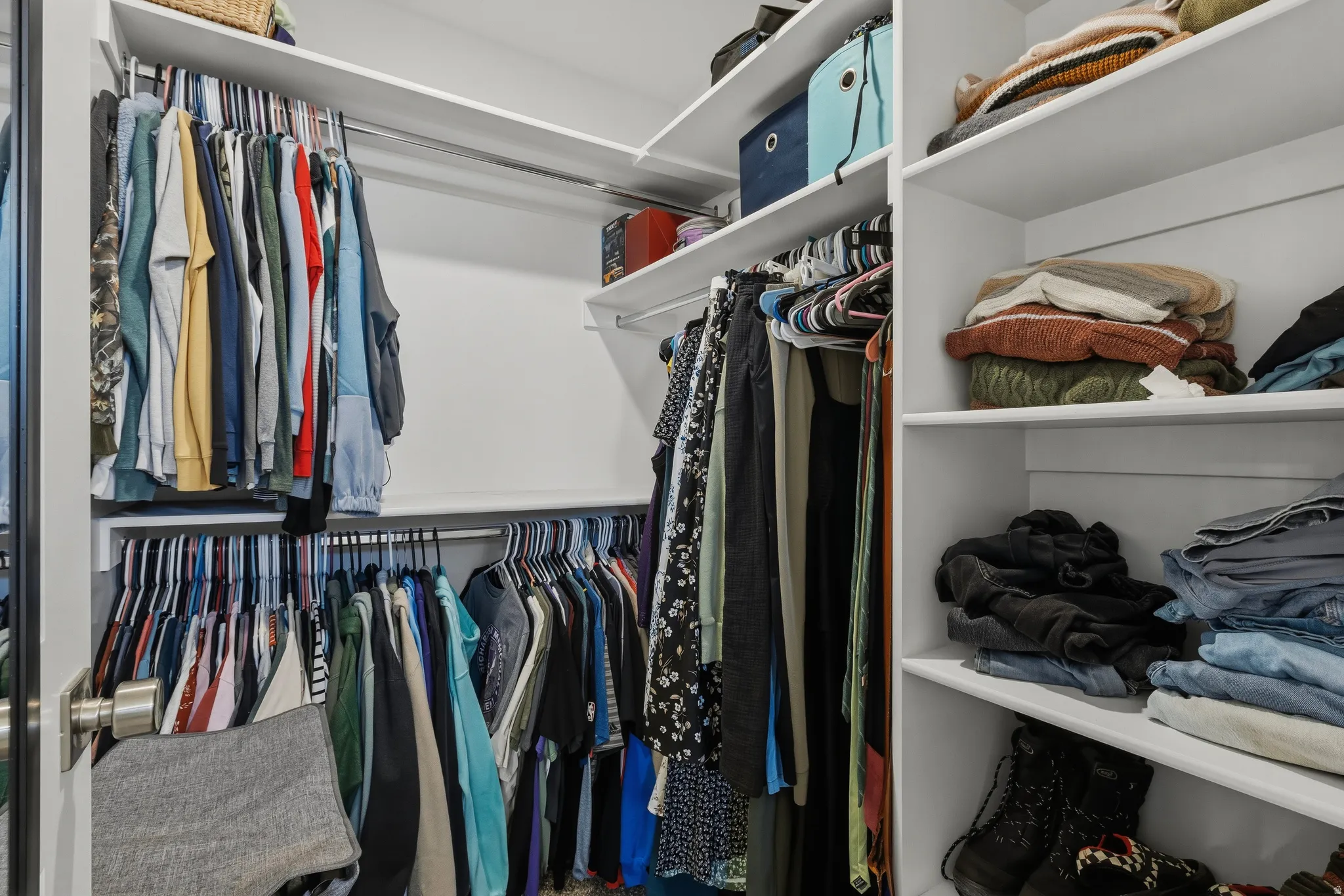 Spacious closet featuring multiple hanging rods, extensive shelving, and white finished walls