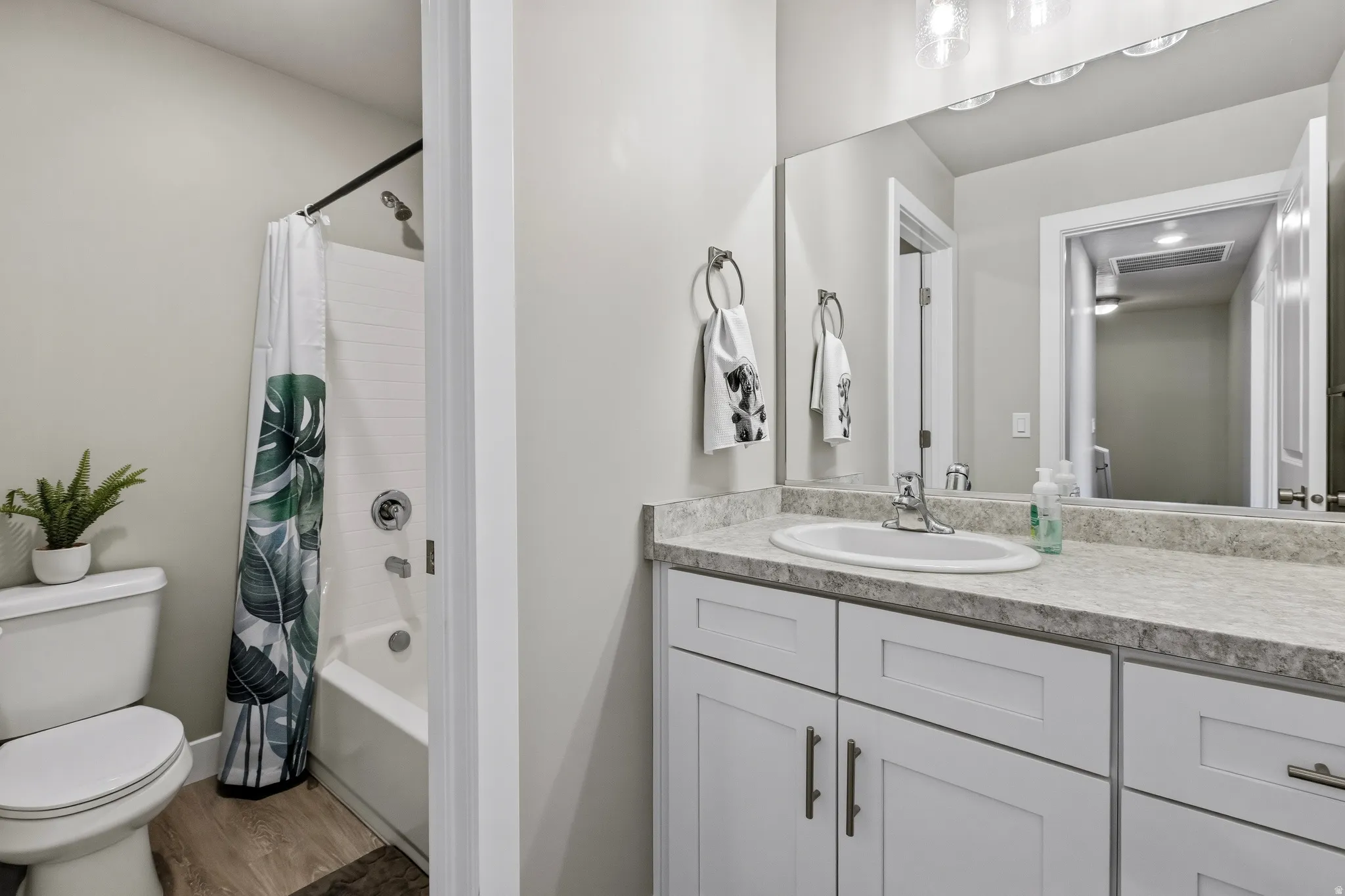 Bathroom vanity featuring white shaker-style cabinetry, a light-toned countertop, and an undermount sink