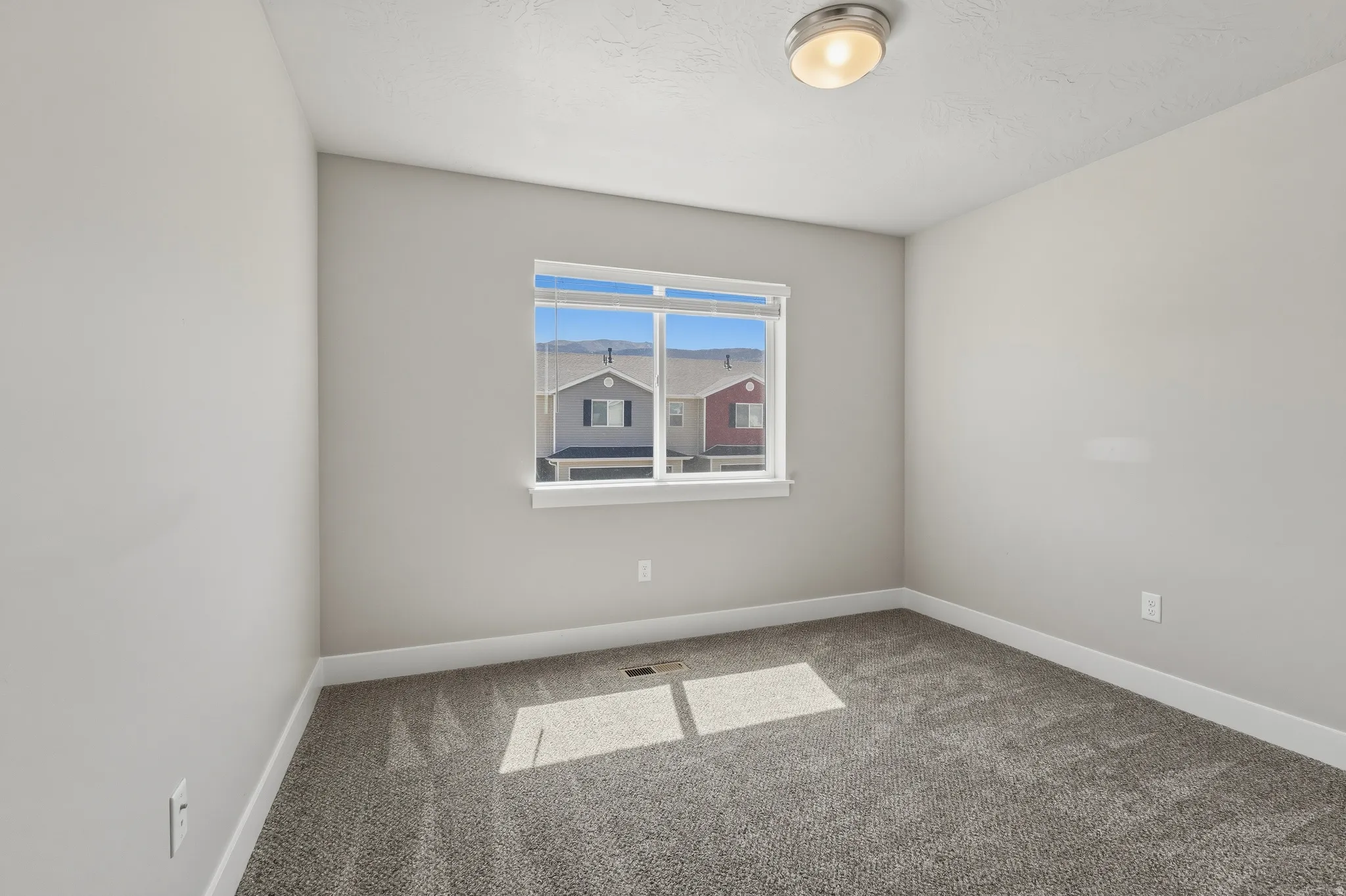 Bedroom featuring neutral wall paint, gray carpet flooring, a window with horizontal blinds, and a flush-mount ceiling light fixture