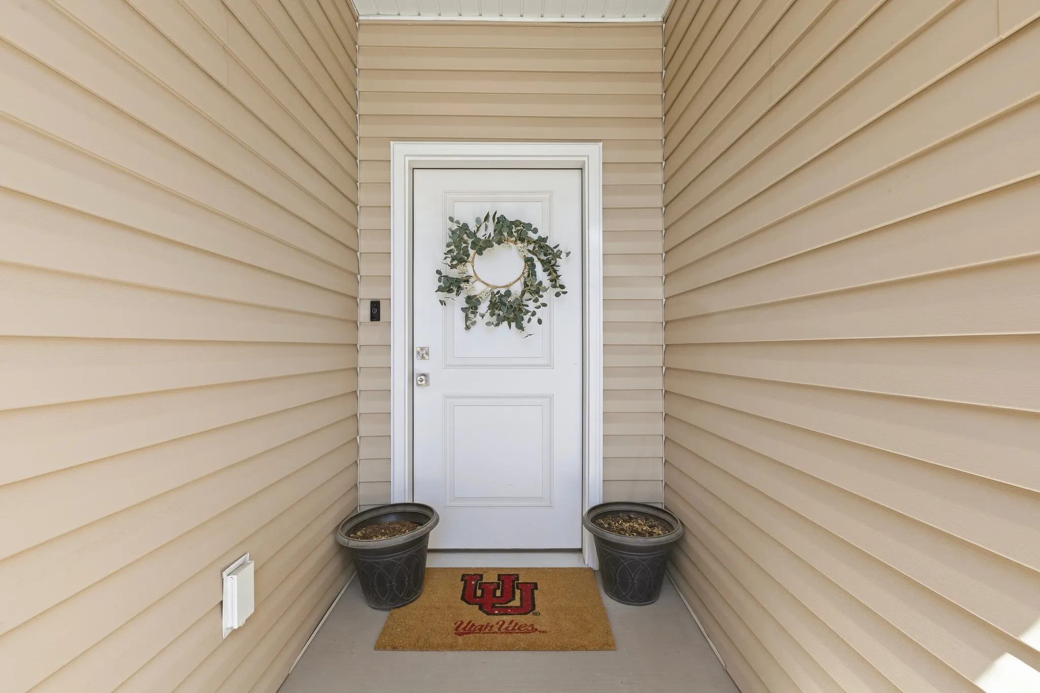 Recessed entry featuring a white paneled door, light-colored horizontal siding, and a concrete porch