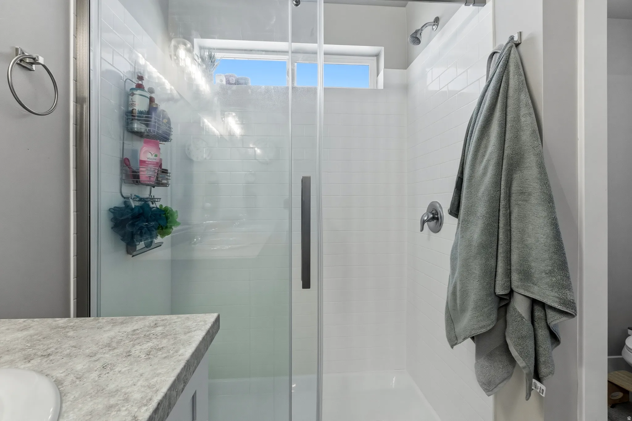 Enclosed shower featuring a clear glass door, white tile surround, and a chrome shower head