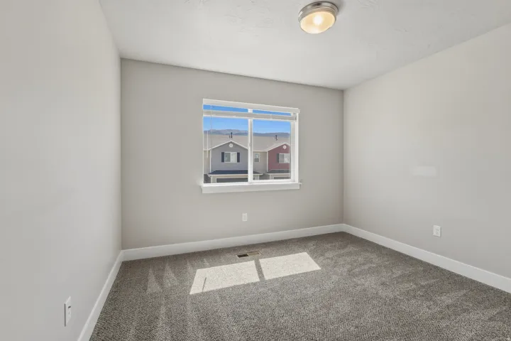 Bedroom featuring neutral wall paint, gray carpet flooring, a window with horizontal blinds, and a flush-mount ceiling light fixture