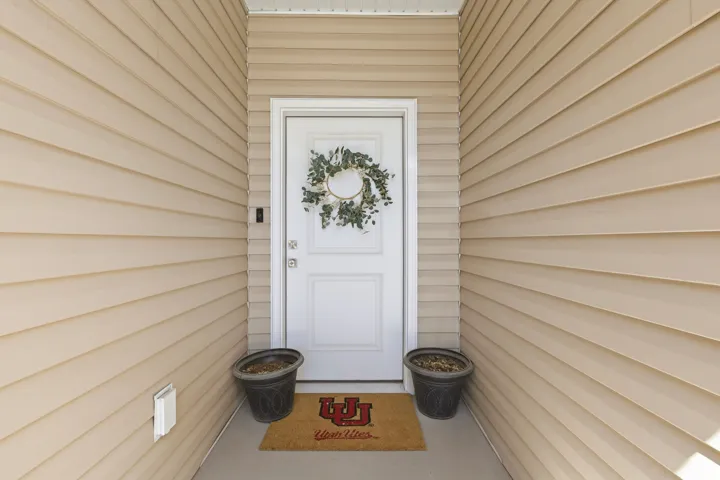 Recessed entry featuring a white paneled door, light-colored horizontal siding, and a concrete porch
