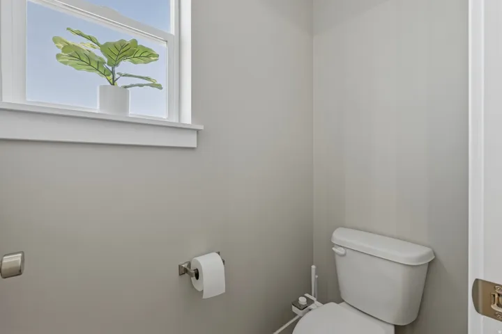 Bathroom featuring a single window with white trim, light gray walls, and a white toilet