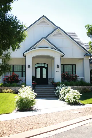 Modern farmhouse exterior with a prominent arched entry and black double doors