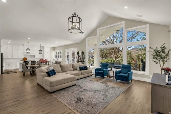 Expansive living area featuring a vaulted ceiling with decorative lighting, large-format windows, and wood-finish flooring