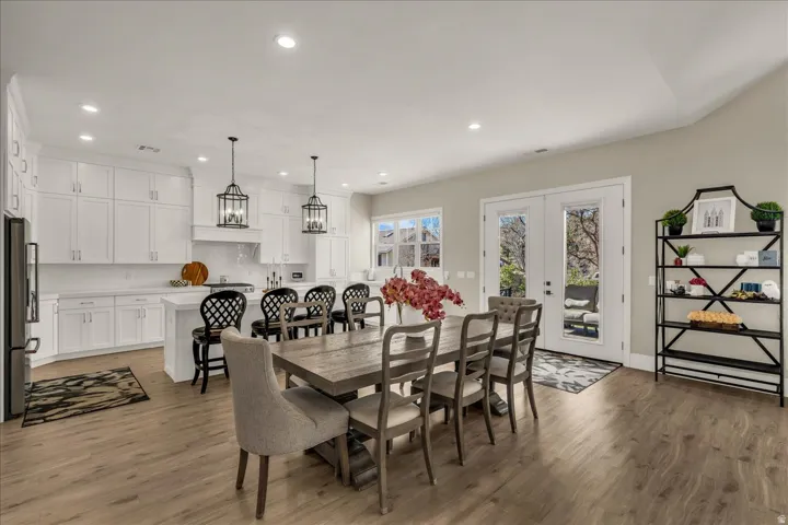 Open-concept kitchen and dining area featuring light wood-finish flooring, recessed lighting, and a white kitchen island with seating