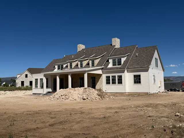 Stone and siding exterior with multiple dormers, a covered porch, and a shingle roof