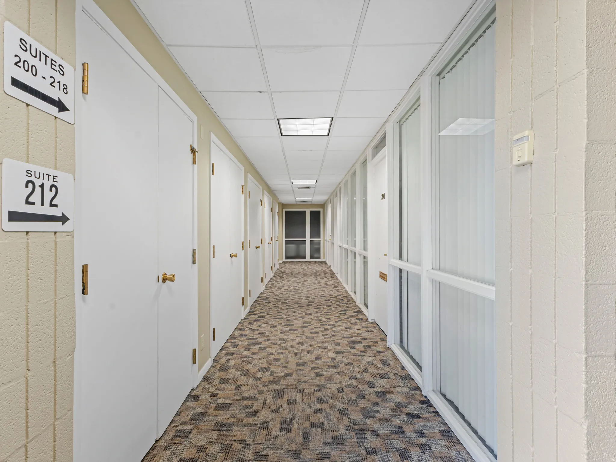 Interior corridor featuring patterned carpet flooring and white acoustic ceiling tiles
