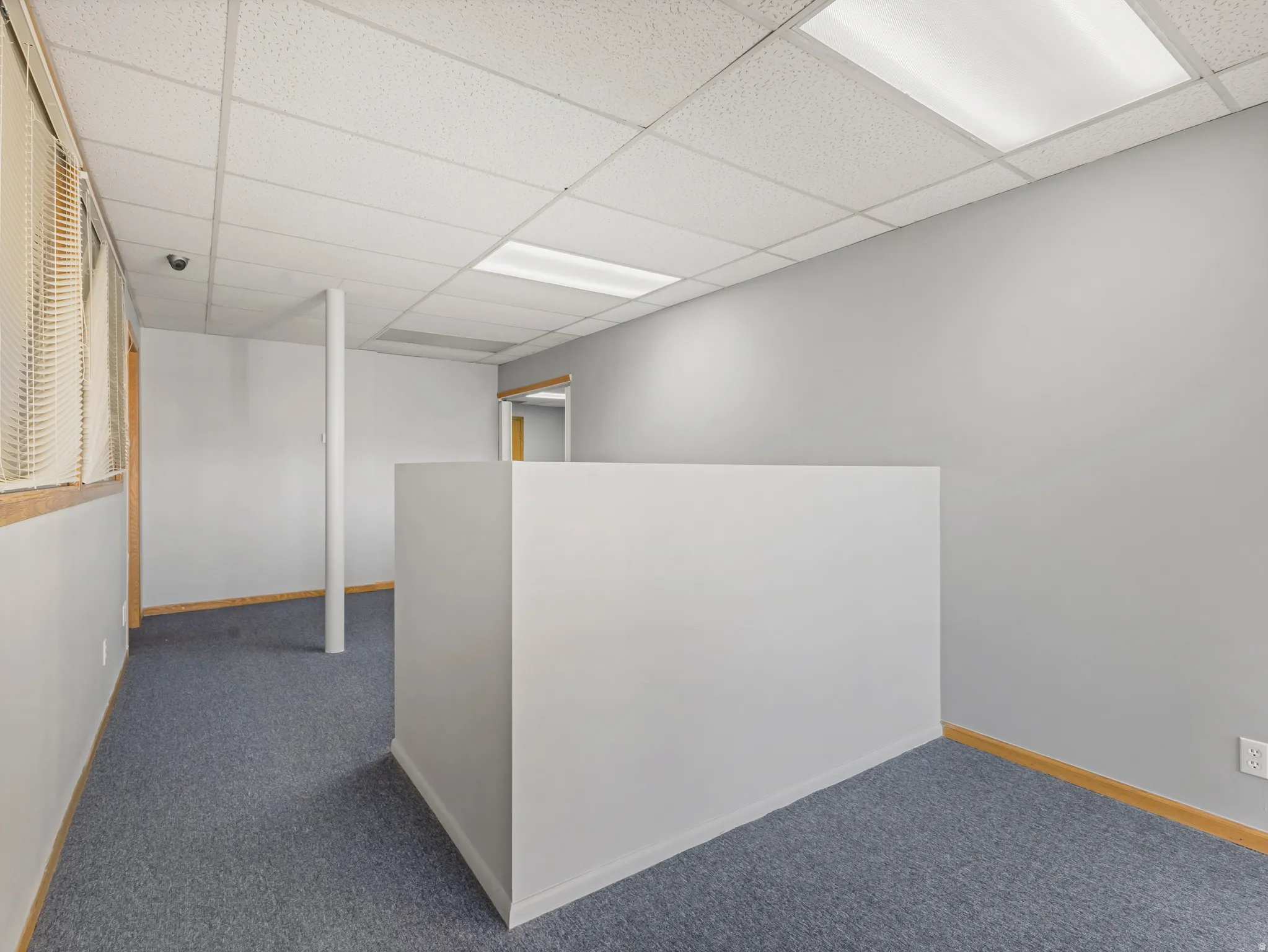 Interior space featuring blue carpeting, light gray walls, and drop ceilings with recessed lighting