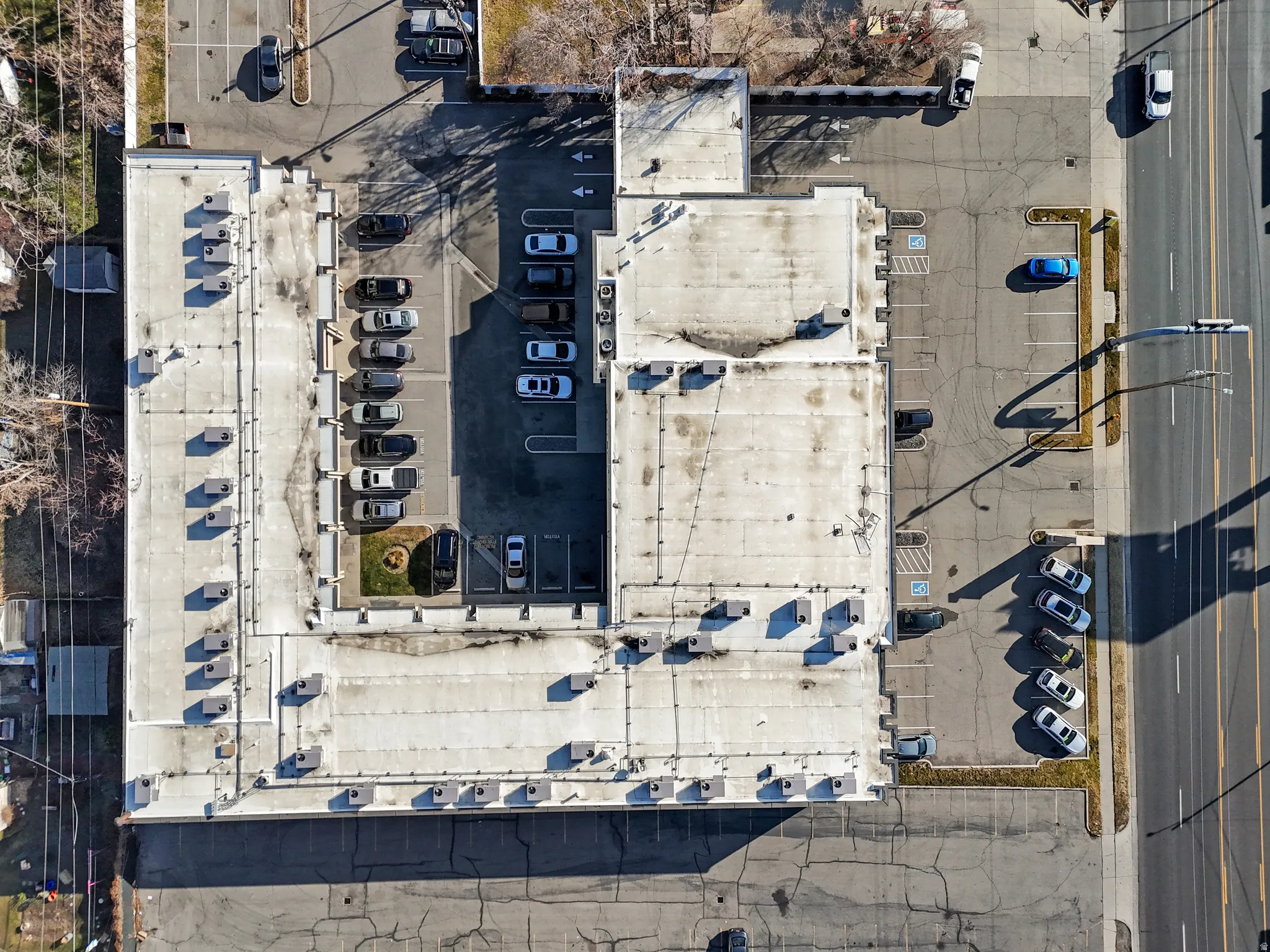 Expansive commercial building featuring a flat roofline, numerous rooftop HVAC units, and multiple integrated parking areas