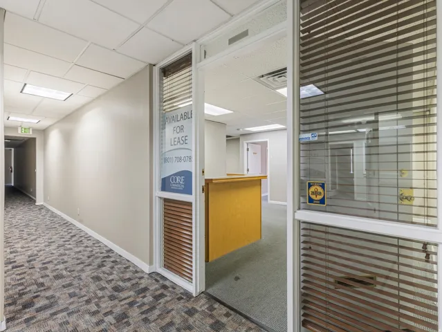 Commercial office space featuring a glass entrance door with blinds, textured carpet flooring, and recessed ceiling lighting